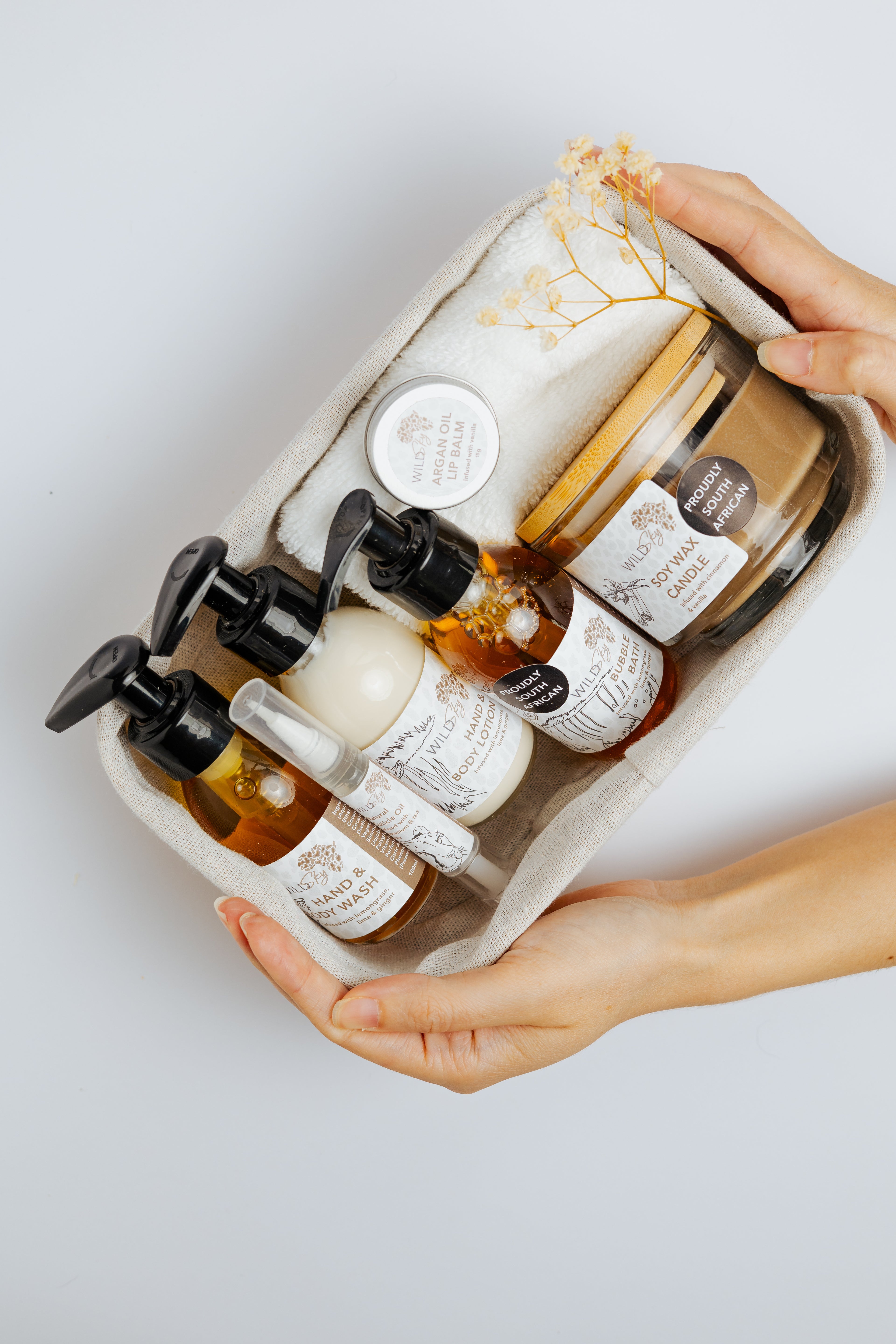 Hand holding a set of skincare products in a white tray on a light gray background