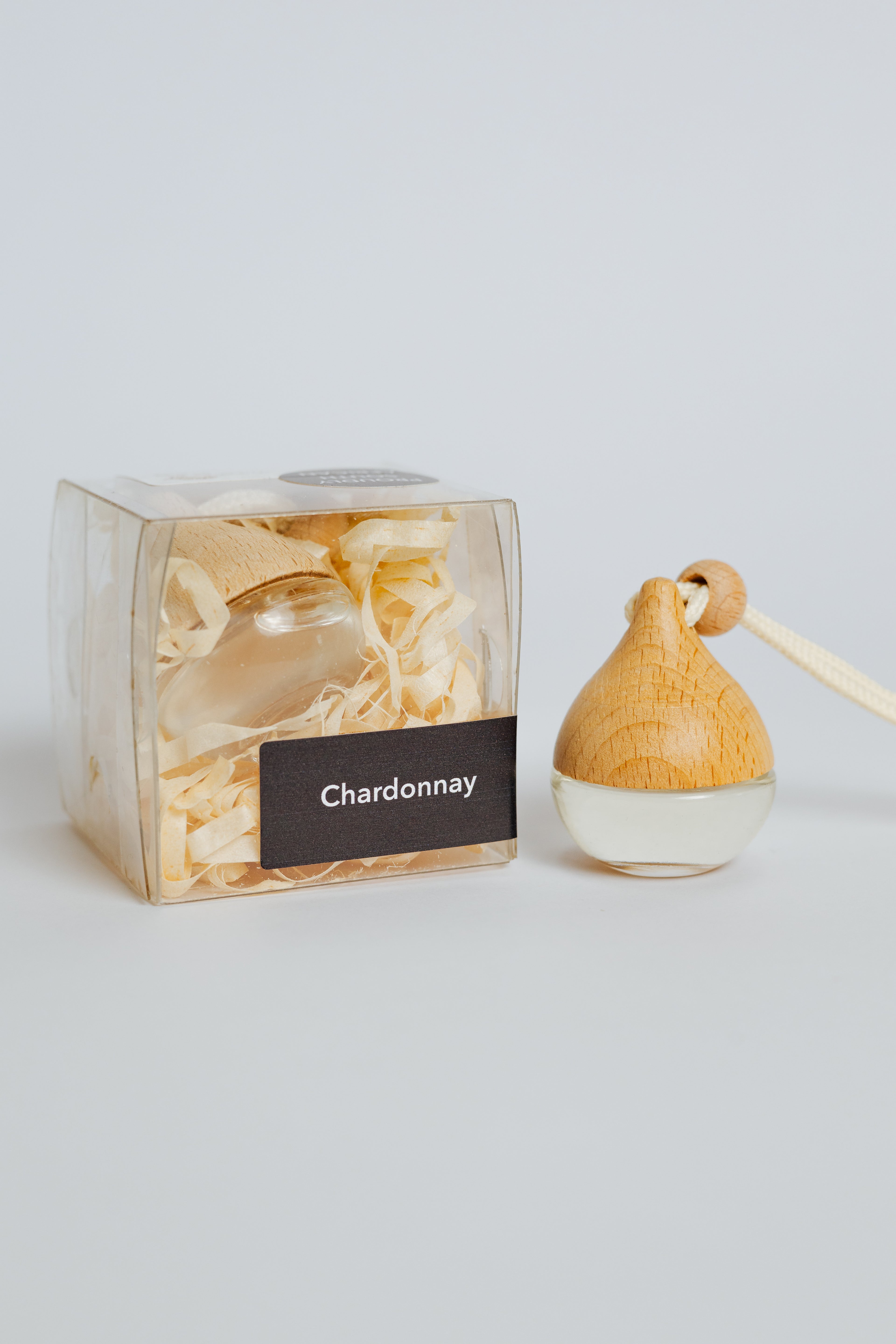 Wooden diffuser with 'Chardonnay' label next to its packaging on a light gray background